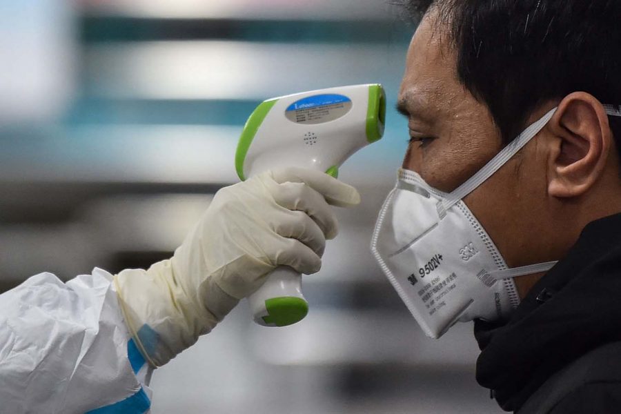 A medical staff member takes the temperature of a man at the Wuhan Red Cross Hospital in China on Jan. 25. HECTOR RETAMAL/AFP via Getty Images